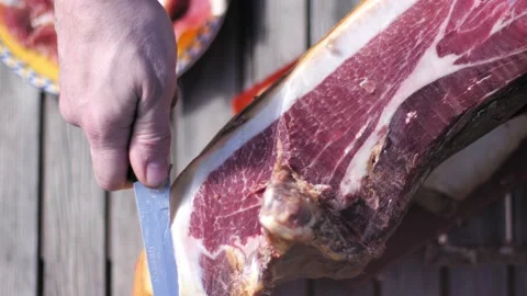 High angle view of man hand cutting a slice of spanish jamon serrano on table. 스톡 동영상 152313088