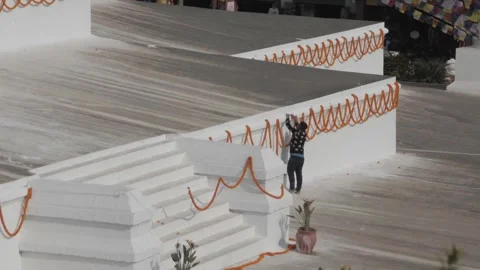High angle view of man hanging chains of marigold rosaries on the wall of Boudha Stock Footage 241736078