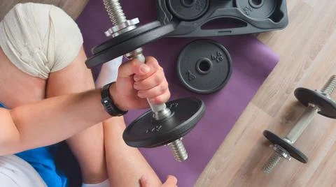 High angle view of a man lifting an adjustable dumbbell sitting on a purple m Stock Photos
