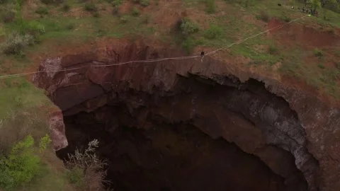 High angle view on a man sitting on the slackline over a huge quarry, 4k Stock Footage 133557846