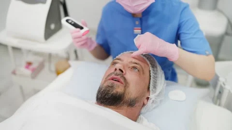 High-angle view of a mature man receiving an ultrasonic face cleaning proce.. Stock Footage 345084468