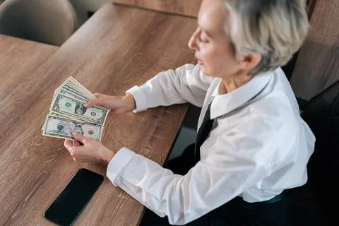 High-angle view of middle-aged woman counting cash money dollars enjoying Stock Photos