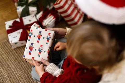 High Angle View of Mother and Child Opening Nutcracker Pattern Wrapped Chri.. Stock Photos