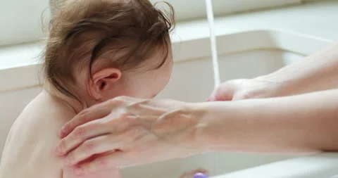 High angle view of a mother giving her baby a bath in kitchen sink. Stock Footage 130355832