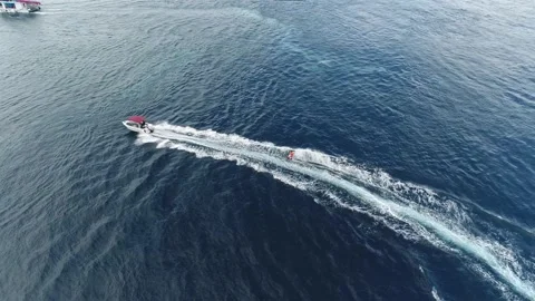 High angle view on the motorboat sailing in the ocean and a man wakeboarding, 4k Stock Footage 136805577
