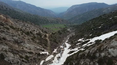 High angle view of mountain gorge with melting snow in riverbed and rocky cliffs Vidéo 334326641