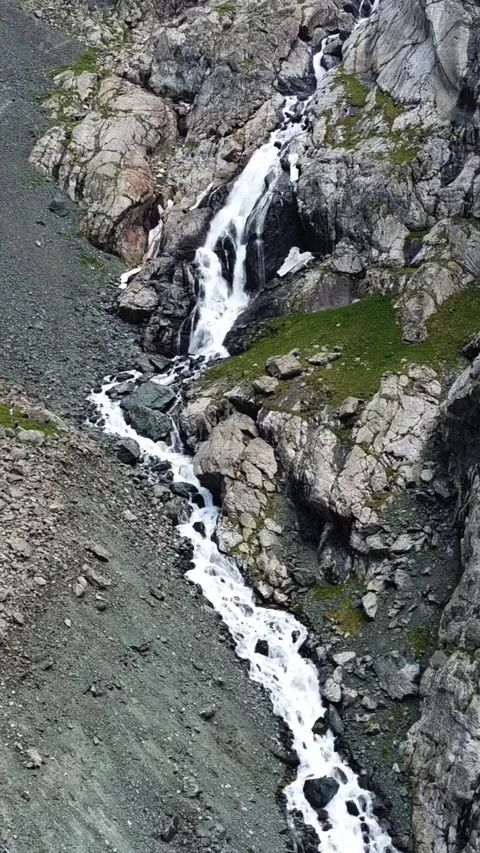 High angle view of mountain waterfall cascading through rocky gorge with trail Stock Footage 336684594