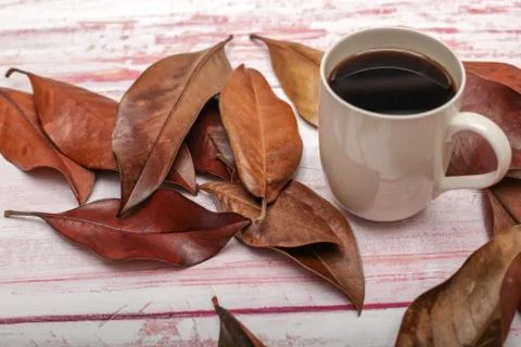 High angle view of  a mug of coffee with autumn leaves on rustic wooden backg Stock Photos