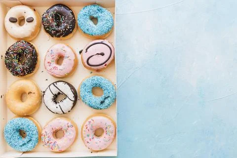 High angle view multi colored fresh donuts box blue background Stock Photos