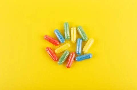High angle view of multicolored oval pills against yellow background. Concept of Stock Photos