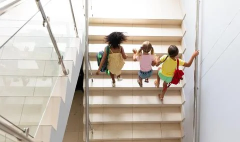High angle view of multiracial elementary schoolgirls climbing steps in school Foto stock