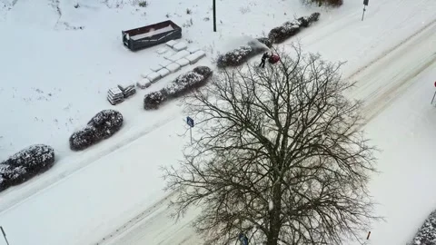 High-angle view of a municipal worker clearing snow from a public sidewalk with Stock Footage 345698662