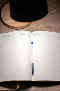 High angle view of an open blank diary on a wooden desk illuminated by a lamp. Stock Photos