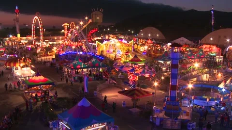 A high angle view over a brightly lit amusement park with many rides and Stock Footage 41982162