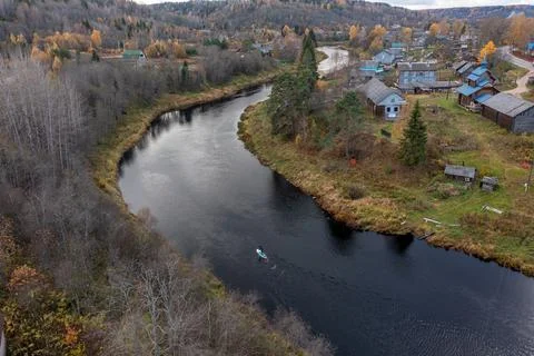 High angle view of a paddleboarder on a tranquil dark river flowing past a Stock Photos