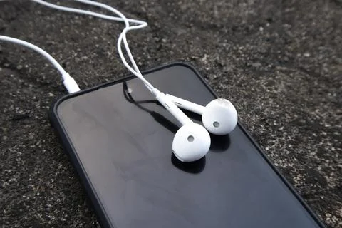High angle view of a pair of classic white wired earphones plugged into a s.. Stock Photos