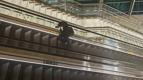 A high-angle view of a person in black attire descending a modern Video stock 333290239