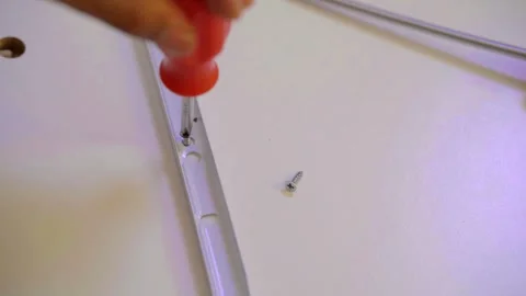 High angle view of a person tightening a screw with an orange screwdriver Видео 323390907