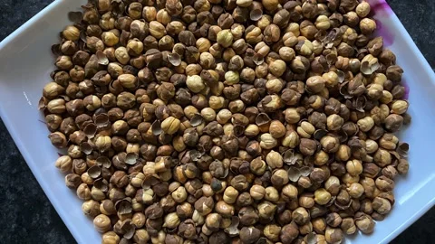 High angle view of a pile of roasted chickpeas served on a white square plate 스톡 동영상 328441272