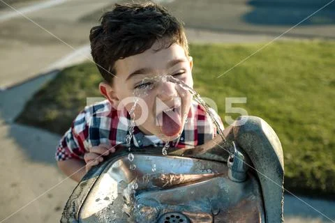 High angle view of playful boy drinking water from fountain Stock Photos