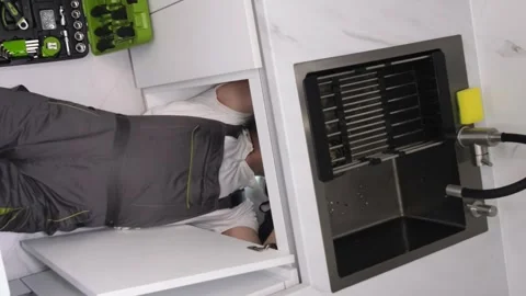 High angle view of plumber laying on floor repairing kitchen sink with tool box Stock-Footage 250027496