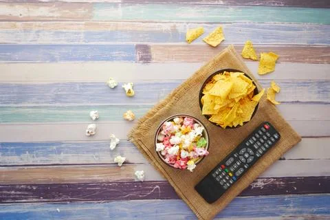 High angle view of popcorn, chips and Tv remote on table Stock Photos