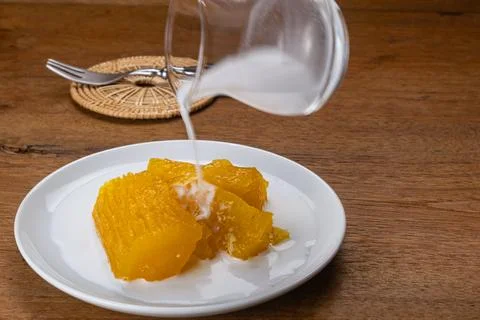 High angle  view pouring coconut milk on cassava or tapioca in syrup. Stock Photos