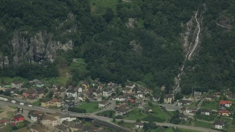 High angle view of Preonzo village beneath tree-lined Alps with waterfall. Stock Footage 86756913