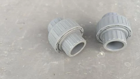 A high angle view presents two grey PVC plastic union pipe fittings resting.. Stock Photos