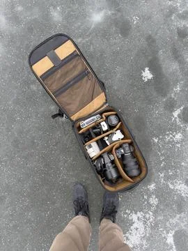 High angle view of professional camera backpack with gear and feet of photo.. Stock Photos