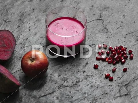 High Angle View Of Purple Raw Juice, Halved Beetroot, Apple And Pomegranate