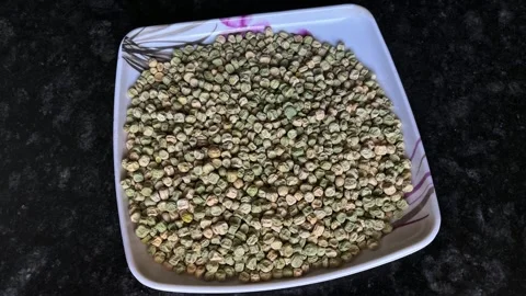 High-angle view of raw dried green peas (Matar) served on a white square plate Видео 328441249