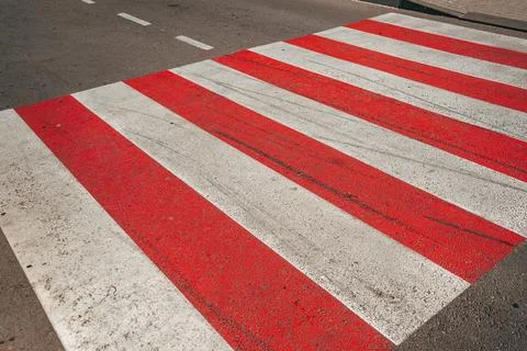 High-angle view of a red and white zebra pedestrian crosswalk painted on a .. 스톡 사진