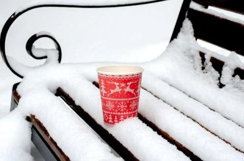 High angle view of red coffee cup on  a bench  covered with  snow  in park. Stock Photos