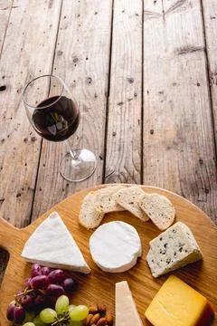 High angle view of red wine with various cheese and grapes on wooden table, copy Stock Photos
