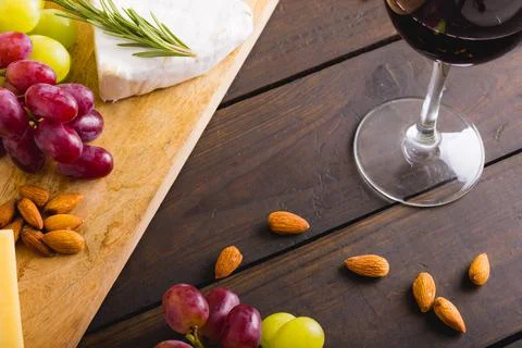 High angle view of red wine by cheese and grapes with almonds on wooden table, Stock Photos