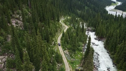 High angle view of off-road car driving on winding dirt road near rushing river Vidéo 334326591