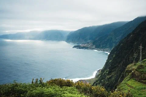 High-angle view of a rugged coastline, vast blue ocean, and a small settlemen Stock Photos