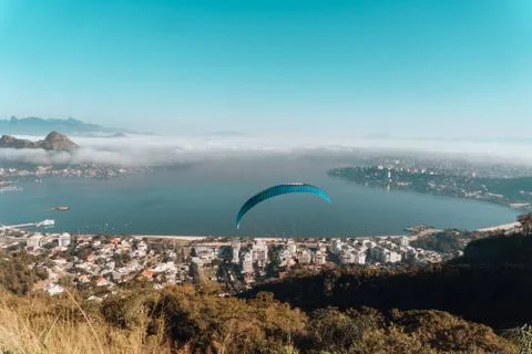 A high angle view of the sea surrounded by buildings and hills with paraglide Fotos de archivo