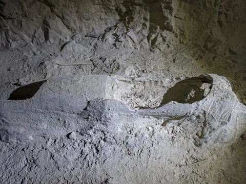 High angle view shows damaged old concrete pipe in dusty floor of rock tunnel Stock Photos