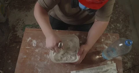 High angle view of a skilled builder mixing plaster with water in a container Stock Footage 327168776