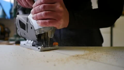 High angle view of skilled carpenter in overalls using speed jig saw to cut Stock Footage 152347398