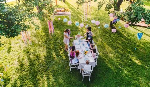 High angle view of small children sitting at the table outdoors on garden party. Stock Photos