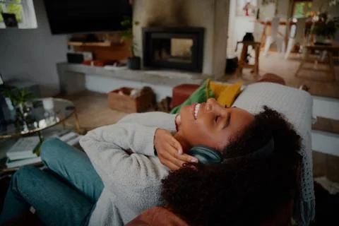 High angle view of smiling african woman relaxing on sofa with headphones Stock Photos