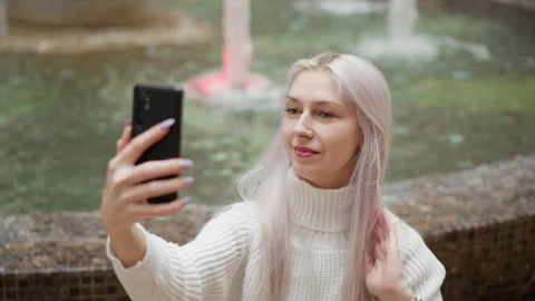High angle view stylish trendsetter adjusts hair for selfie by mall fountain Stock Footage 316816317
