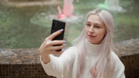 High angle view stylish trendsetter adjusts hair for selfie by fountain Stock Footage 316816429