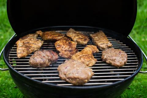 High angle view of succulent steaks and burgers cooking on a barbecue Stock Photos