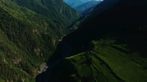 High Angle View of Sunlit Green Hills with Serpentine Road Cutting Through Dense Stock Footage 265592900