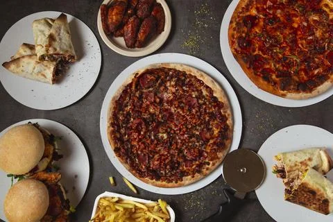 High angle view of table with various pizzas and burgers Stock Photos