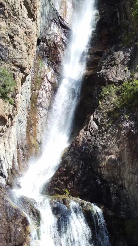 High angle view of tall waterfall cascading between rocky cliffs and  trees Видео 336691777